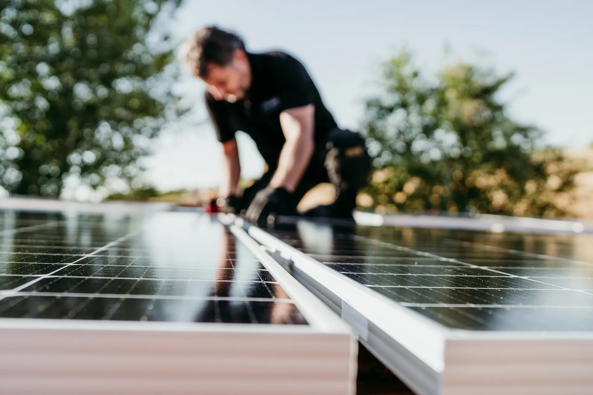Reifer Techniker bei der Montage von Solarzellen auf dem Hausdach für den Eigenverbrauch von Energie. Erneuerbare Energien und grüne Energie